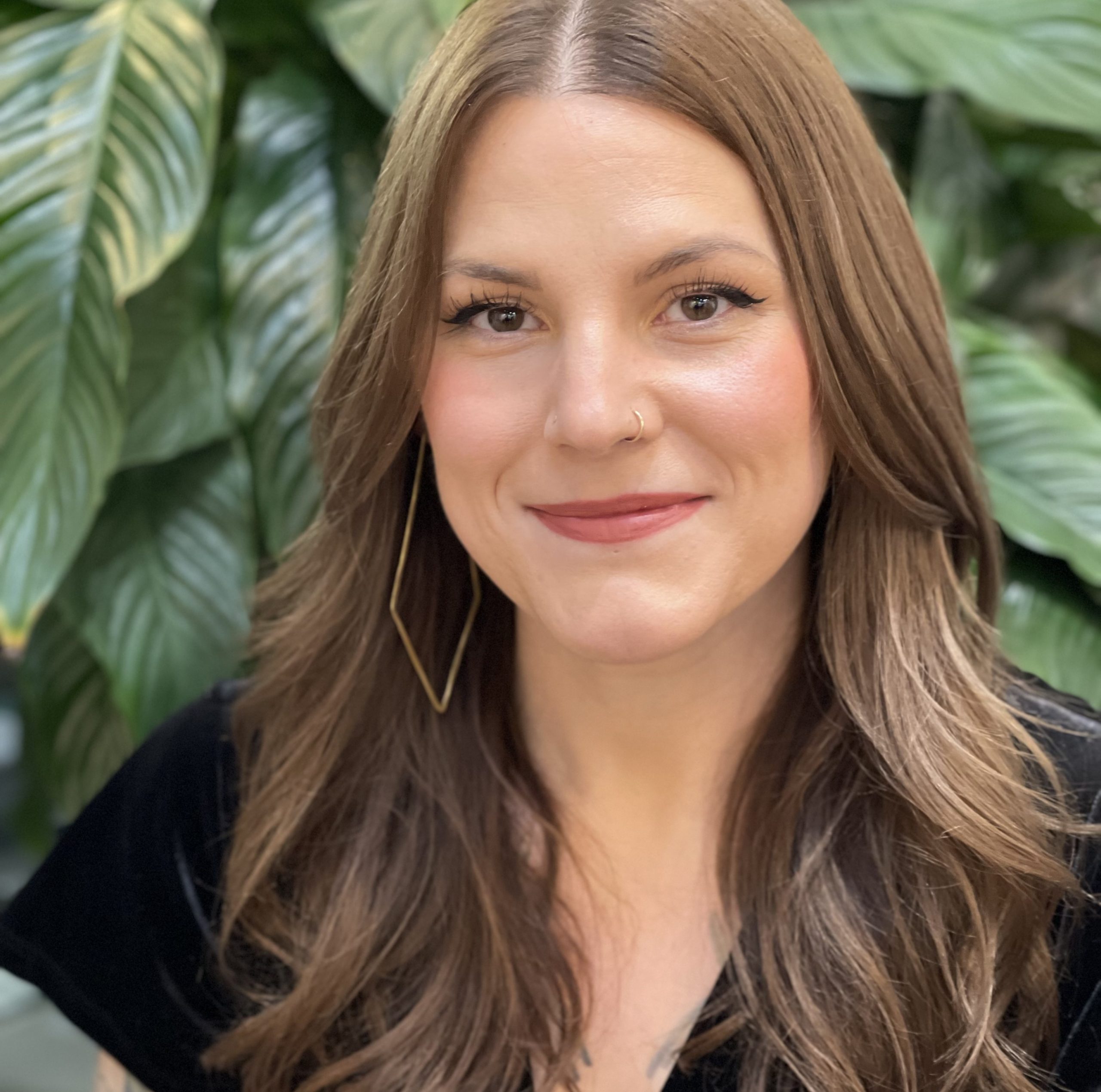 Taylor Vickers sitting in front of a plant at Infinite Salon in Portland, OR